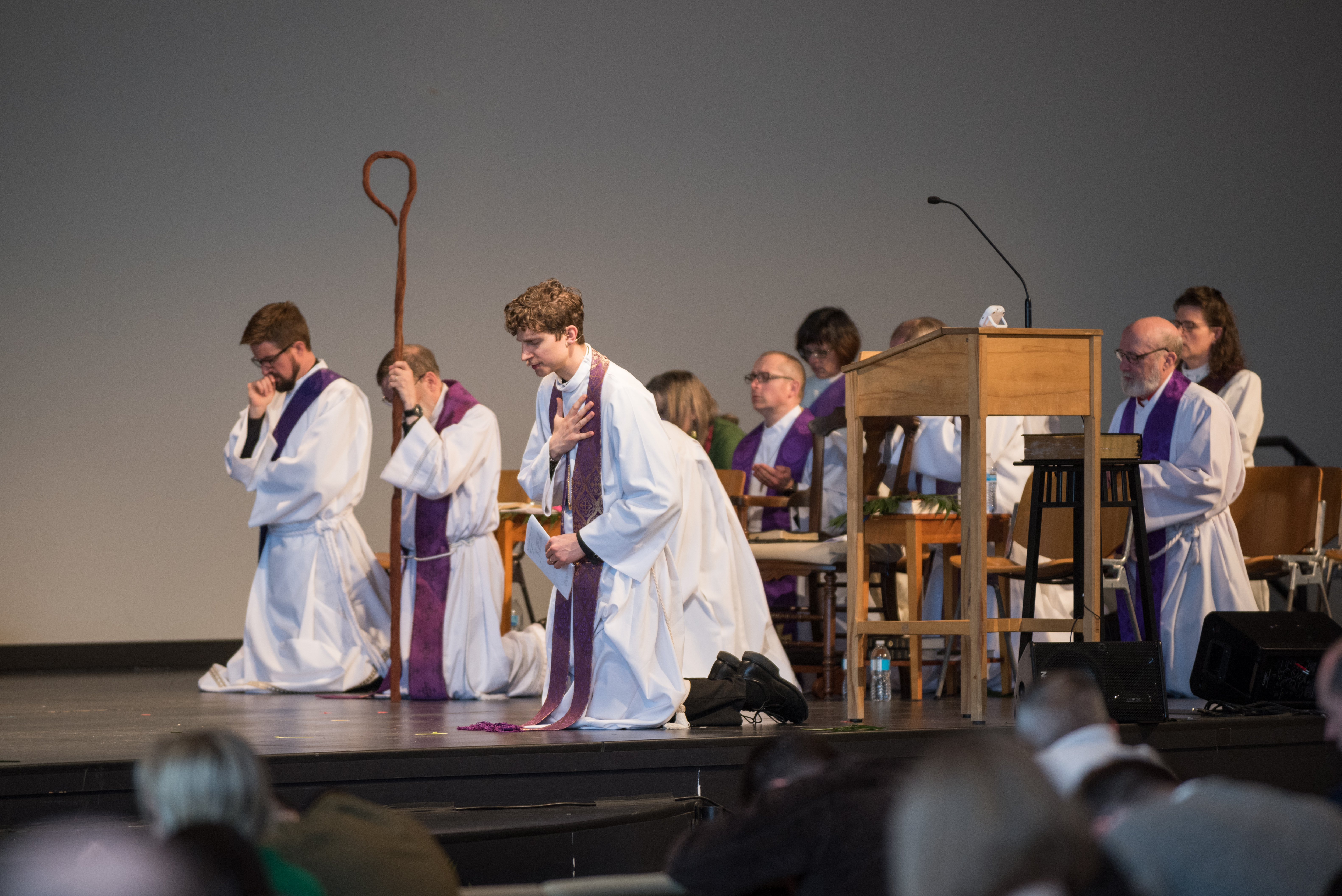 Kneeling clergy in robes on church stage
