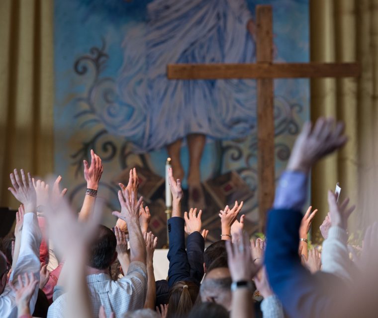 Hands raised in worship before the cross