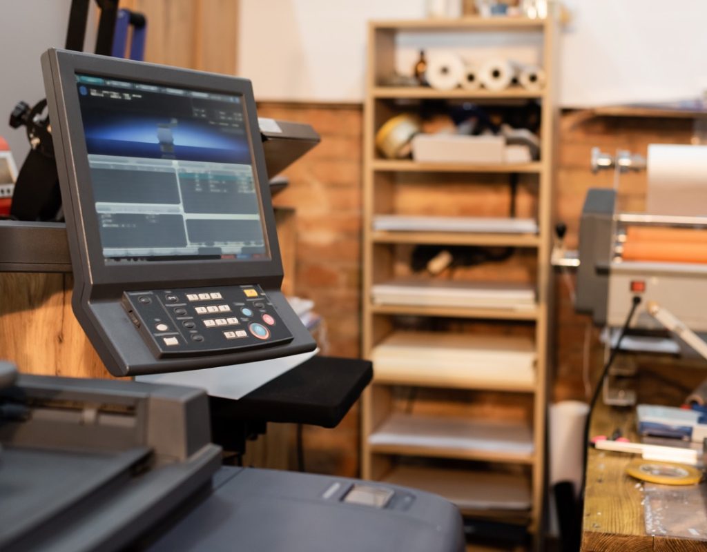 modern printer next to monitor and button panel in print center